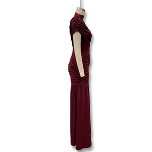 Side view of a burgundy ruched bodycon dress with sleek fishtail hem and glossy fabric