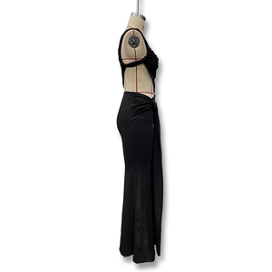 Detail view of black backless maxi dress with elegant side ruching and glossy fabric texture