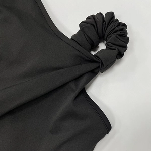 Detail view of black dress showing elastic scrunchie style shoulder strap and knit fabric