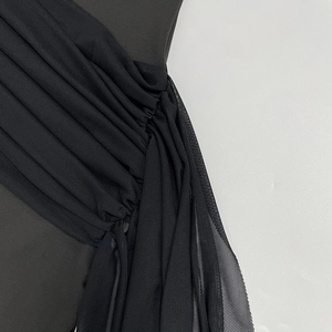 Macro view of black mesh pleats and layered fabric texture on a slim fitted dress