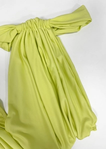 Detailed view of fluorescent green satin fabric with vertical ruched textures and elegant drape