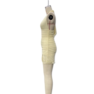Detail view of light yellow ruched mini dress with side pleats and bodycon silhouette
