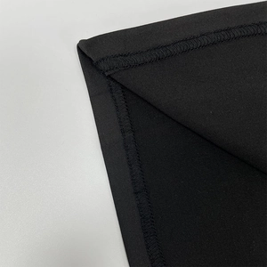 Detailed close-up showing precise overlock stitching on black bodycon dress fabric