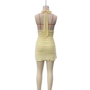 Detail of light yellow halter mini dress with an open back and long ribbon bow