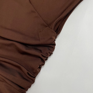 Dettaglio della trama in maglia a coste e design arricciato laterale sull'abito marrone