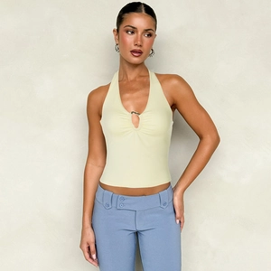 Detail eines hellgelben Neckholder-Tops mit tiefem V-Ausschnitt und Metallring-Element