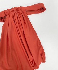 Close-up of rust red off-shoulder dress featuring delicate ruching and soft knit fabric