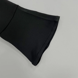 Détail du tissu en maille haute densité et des coutures fines sur la manchette noire évasée