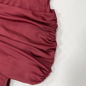 Macro detail of wine red ruching fabric with fine stitching on a sleeveless dress