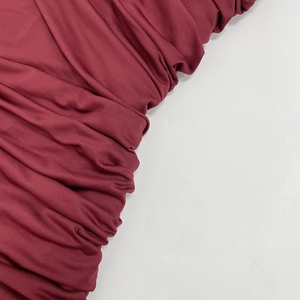 Detailed view of the dark red ruched fabric texture on a slim-fit sleeveless dress