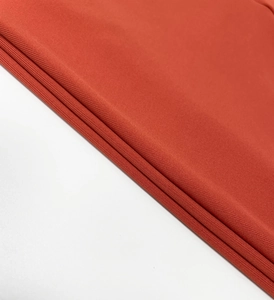 Macro detail of rust red knitted fabric with dense plain weave texture and soft drape