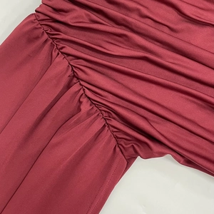 Detailed close-up of ruched fabric and fine stitching on a burgundy sleeveless dress