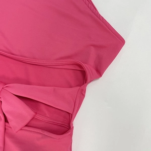 Détail d'une combinaison rose avec design ajouré et nœud papillon 3D sur tissu élastique