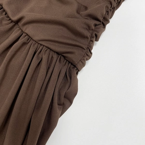 Gros plan sur les fronces et la maille côtelée de cette robe longue marron foncé