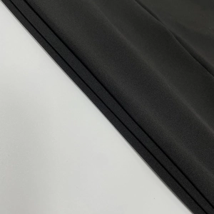 Dettaglio ravvicinato del tessuto a maglia nera con trama verticale e drappeggio raffinato