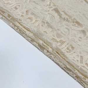 Dettaglio in pizzo floreale beige con ricami raffinati e trama a nido d'ape