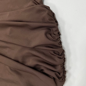 Detailed close-up of side ruched texture on a dark brown sleeveless bodycon dress