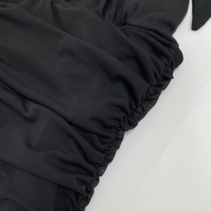 Close-up detail of black sheer mesh fabric with intricate ruched side seam construction