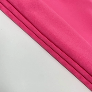 Détail du tissu en maille rose vif avec texture verticale et matière extensible