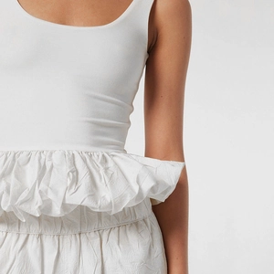 Détail du haut blanc sans manches avec taille à volants superposés et mélange de textures