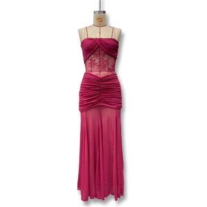 Detail of ruched deep pink maxi dress featuring lace patchwork and sleek mermaid hemline