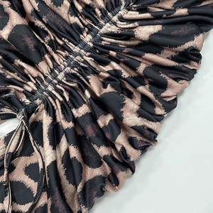 Detail of leopard print dress featuring side drawstrings and ruched stretch fabric