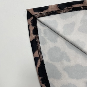 Close-up of leopard print dress fabric showing high-quality black overlock stitching detail