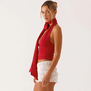 Detail of red halter top with scarf and white high-waisted ruffled shorts texture