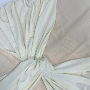 Detailed close-up of cream mesh fabric showing elegant knots and soft draping textures