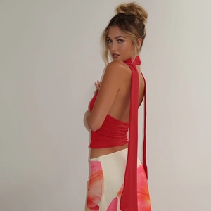 Detail of red halter top featuring long neck ties and backless slim fit design