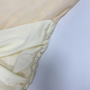 Detail view of beige fishnet mesh stitching and pleated fabric on a slim mermaid dress