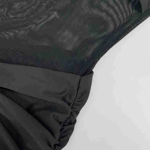 Detailed close-up of black sheer mesh stitching and ruched fabric texture on a fishtail dress