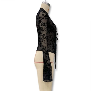 Detailed view of black lace blouse with sheer floral velvet motifs and tie-up front