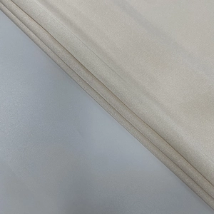Close-up detail of beige lace fabric showing intricate textile texture and soft weave
