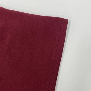 Détail du tricot bordeaux montrant la couture à double aiguille et la texture du tissu