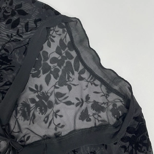 Detail shot of sheer black floral mesh fabric with high-quality embroidery and hem stitching