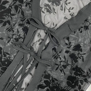 Detail of sheer black mesh top featuring rose floral print and delicate lace-up V-neckline