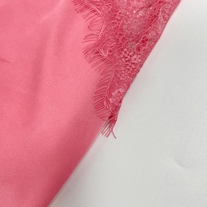 Detailed close-up of pink satin fabric with delicate eyelash lace trim and silky texture