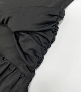 Detaillierte Nahaufnahme der eleganten seitlichen Raffung eines schwarzen Strickkleides