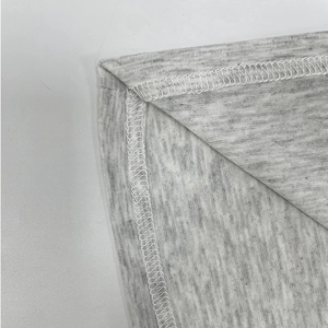 Détail du tissu tricoté gris chiné avec couture surjet blanche précise sur le bord