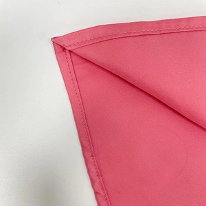 Macro shot of rolled hem stitching on the pink silk fabric of the deep V-neck dress