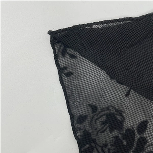 Detailed macro view of black sheer mesh fabric with intricate floral prints and neat stitching