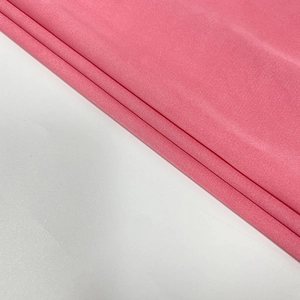 Detailed view of pink silk chiffon fabric with soft sheen and delicate texture on white background