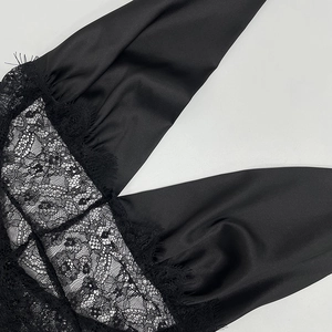 Close-up of black satin fabric with intricate eyelash lace trim and fine stitching detail