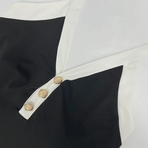 Détail du col en V avec boutons dorés sur le combishort contrasté noir et blanc