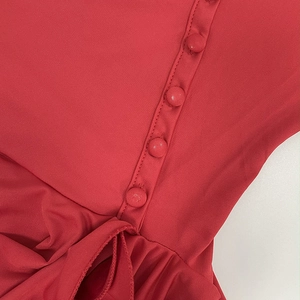 Detailed close-up of red ruffled dress with fabric-covered buttons and fine knit texture