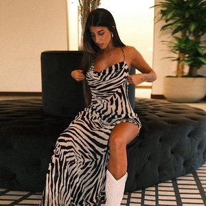 Detail of zebra print dress with high side slit and cowl neck draped on velvet sofa