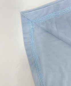 Macro detail of light blue mesh fabric with precise stitching on a slim fit dress