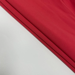 Close-up of bright red knitted fabric texture showing fine ribbing on a slim fit dress