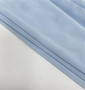 Macro shot of light blue breathable mesh fabric texture and soft pleated details on the dress